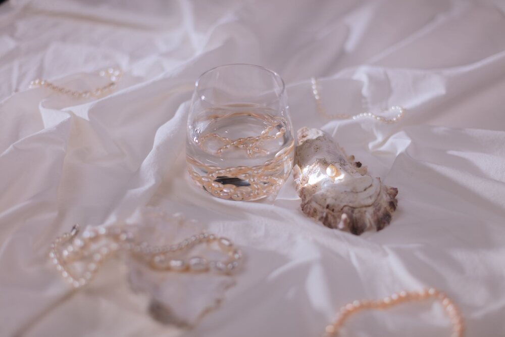 Plusieurs colliers de fantaisie étalés sur un tissu clair légèrement froissé