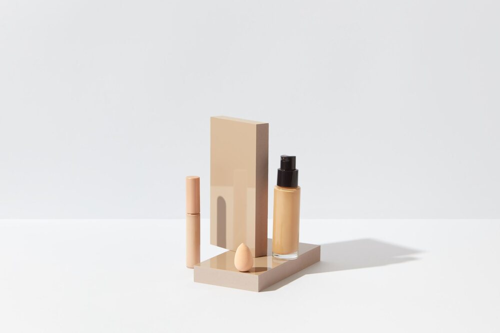 Flacon de fond de teint et éponge humide posés sur une tablette claire
