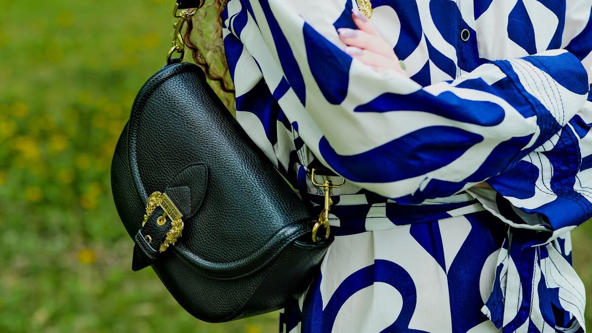 Sac bandoulière en cuir noir porté en travers du buste dans la rue
