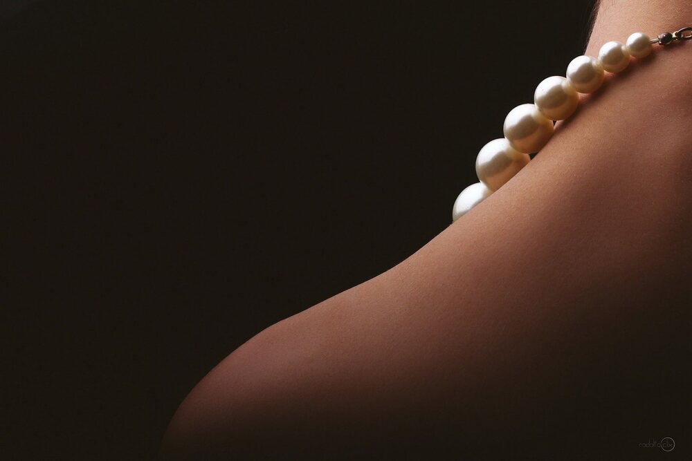 Collier de perles posé en boucle sur un tissu sombre