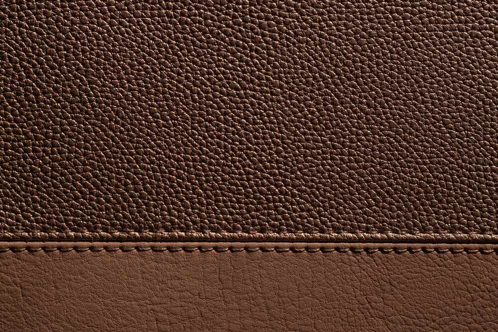 Couture d'un sac en cuir photographiée de près, points réguliers et tranche teintée