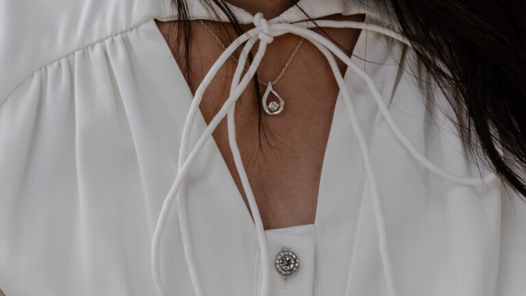 Pendentif en forme de nœud porté sur un chemisier blanc à encolure nouée