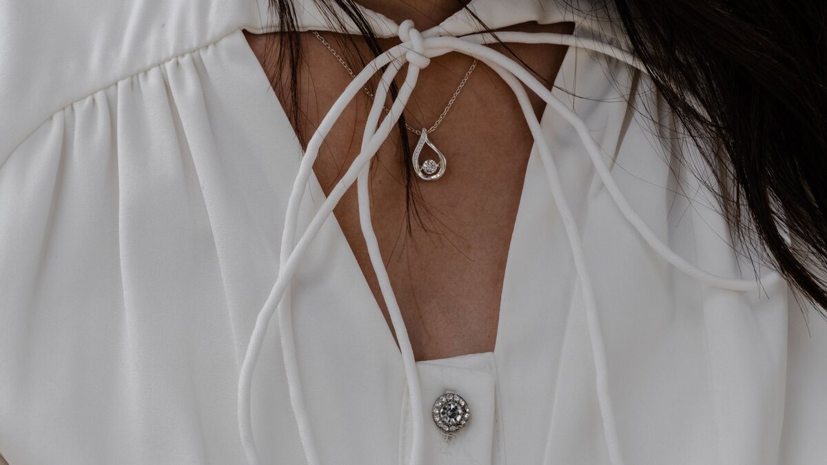 Pendentif en forme de nœud porté sur un chemisier blanc à encolure nouée